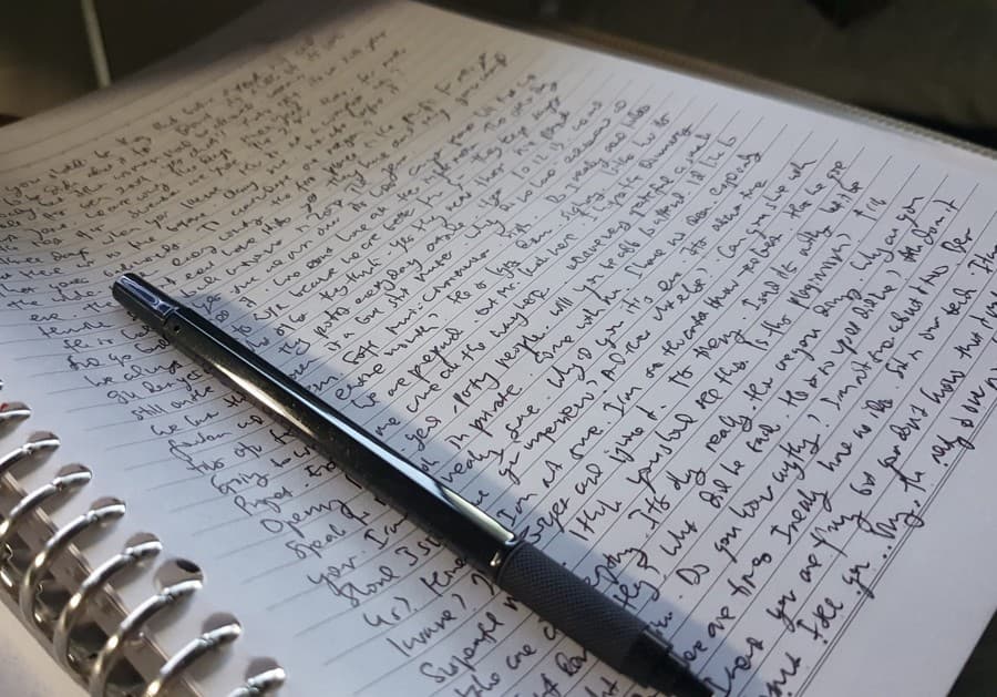 Carnet à spirale rempli d’écriture manuscrite, un stylo posé en travers des pages