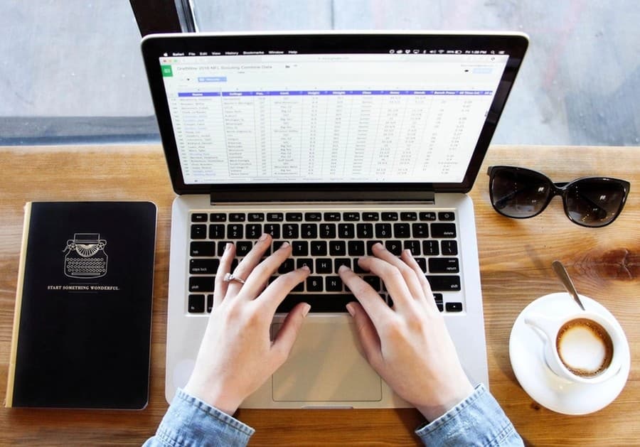 Mains sur le clavier d’un ordinateur portable affichant un tableur